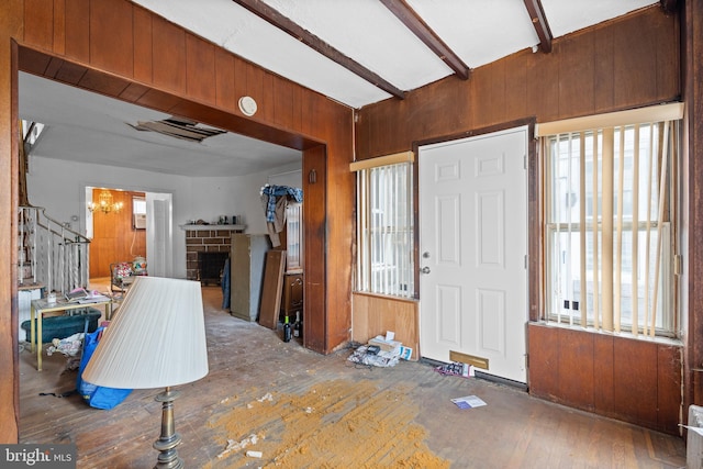 foyer entrance featuring wood walls, hardwood / wood-style floors, beamed ceiling, and a brick fireplace