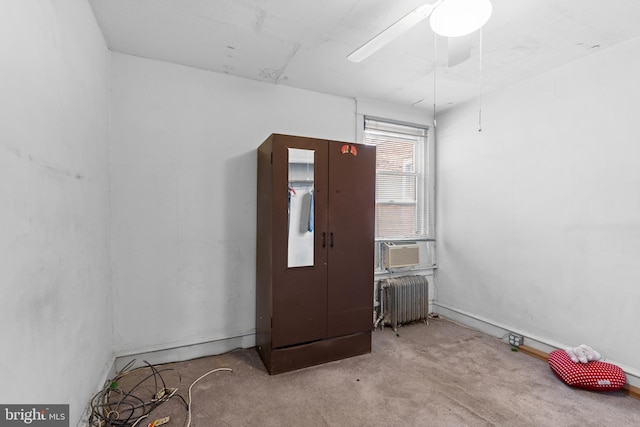 unfurnished room with radiator, light carpet, and ceiling fan