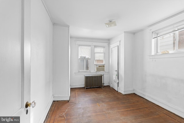 empty room featuring crown molding, radiator heating unit, cooling unit, and dark wood-type flooring