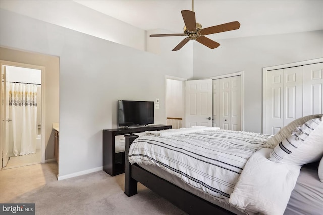 bedroom with ceiling fan, light carpet, high vaulted ceiling, and two closets