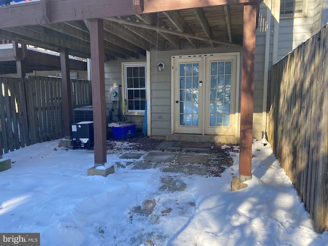 snow covered property entrance with french doors and a carport