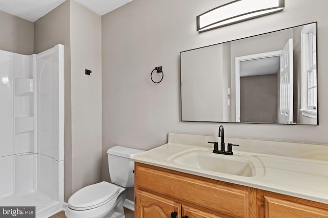 bathroom with vanity, a shower, and toilet