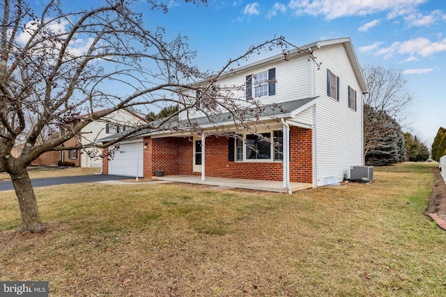 front of property with cooling unit, a garage, a front yard, and covered porch