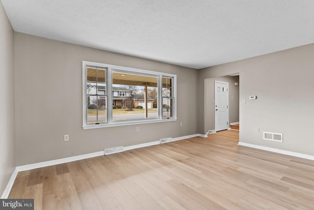 spare room featuring a textured ceiling and light wood-type flooring