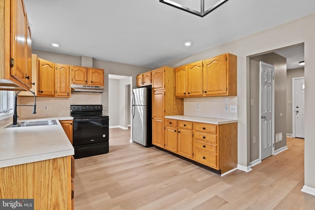 kitchen with black range with electric stovetop, sink, stainless steel fridge, and light wood-type flooring