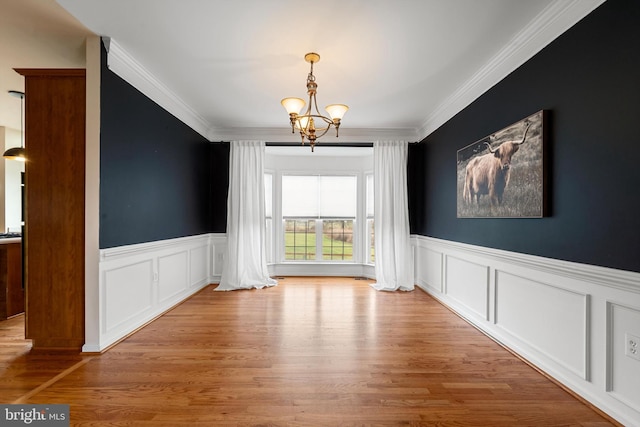 unfurnished dining area featuring a notable chandelier, light hardwood / wood-style floors, and ornamental molding