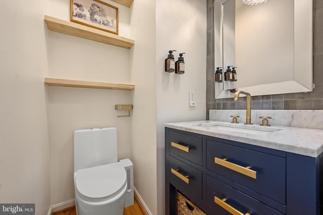 bathroom featuring vanity, toilet, wood-type flooring, and tasteful backsplash