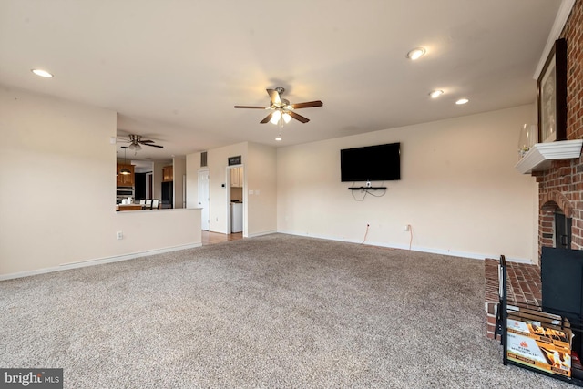 unfurnished living room with carpet, ceiling fan, and a brick fireplace