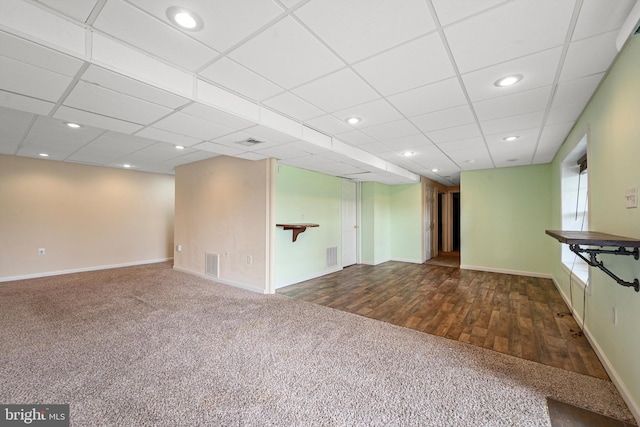 unfurnished living room with a drop ceiling and wood-type flooring