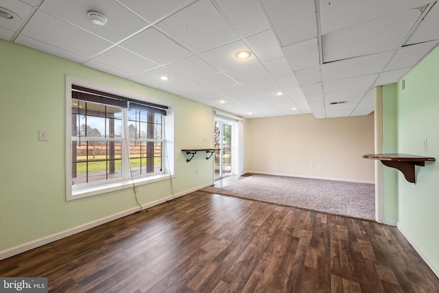 unfurnished living room with a paneled ceiling and dark hardwood / wood-style floors