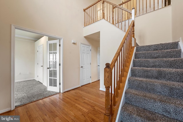 staircase with a towering ceiling and hardwood / wood-style flooring