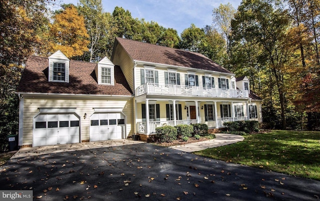 colonial inspired home featuring a porch, a garage, and a front lawn