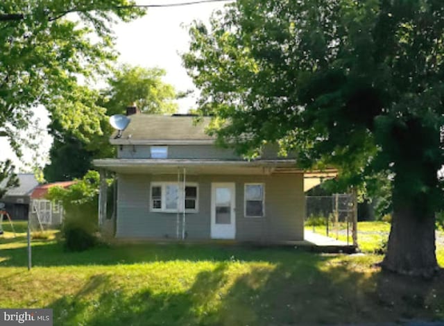 rear view of property featuring a yard and fence