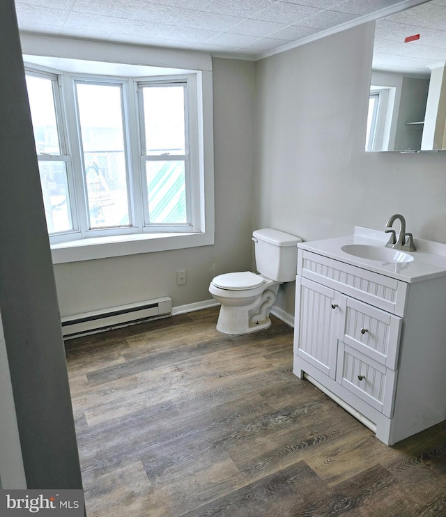 bathroom with vanity, toilet, wood-type flooring, and baseboard heating