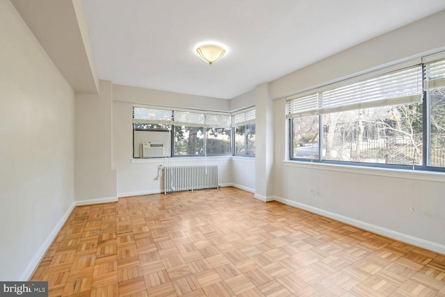 unfurnished room with cooling unit, light parquet flooring, and radiator