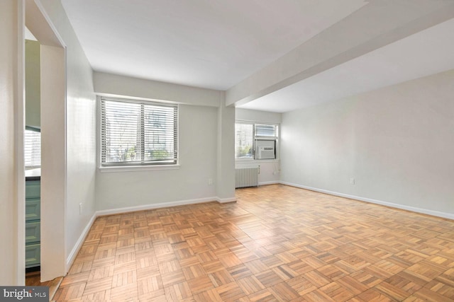 empty room with light parquet flooring, cooling unit, and radiator heating unit