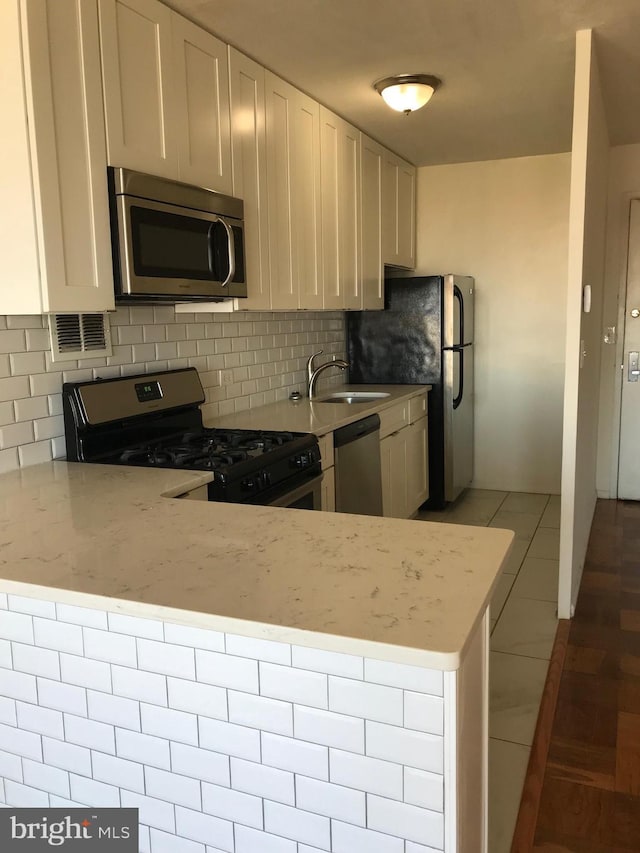 kitchen featuring kitchen peninsula, white cabinetry, stainless steel appliances, and light stone counters