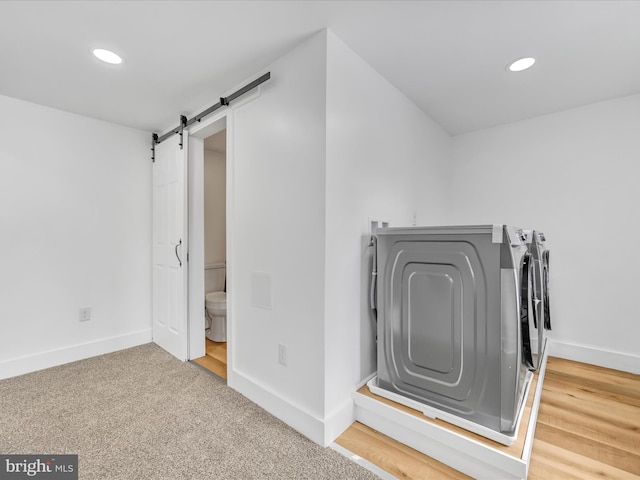 clothes washing area featuring a barn door, separate washer and dryer, and carpet floors