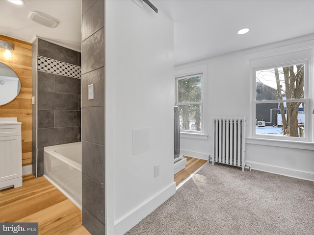 bathroom with a tub to relax in, radiator, a wealth of natural light, and vanity