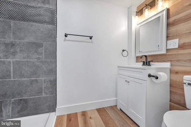 bathroom with hardwood / wood-style flooring, vanity, wood walls, and toilet