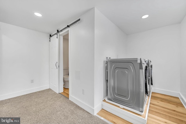 laundry room with a barn door, carpet floors, and washer and clothes dryer