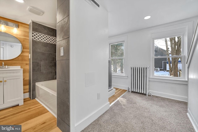 bathroom featuring radiator, plus walk in shower, and vanity