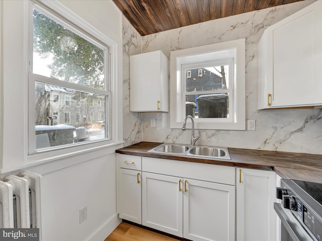 kitchen with radiator, sink, white cabinets, and wooden ceiling