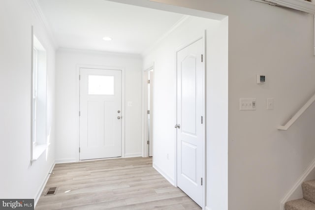 foyer with crown molding and light hardwood / wood-style floors