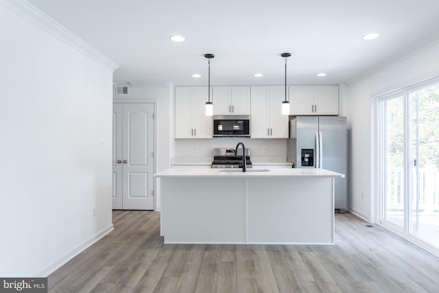 kitchen with sink, stainless steel appliances, pendant lighting, a kitchen island with sink, and white cabinets