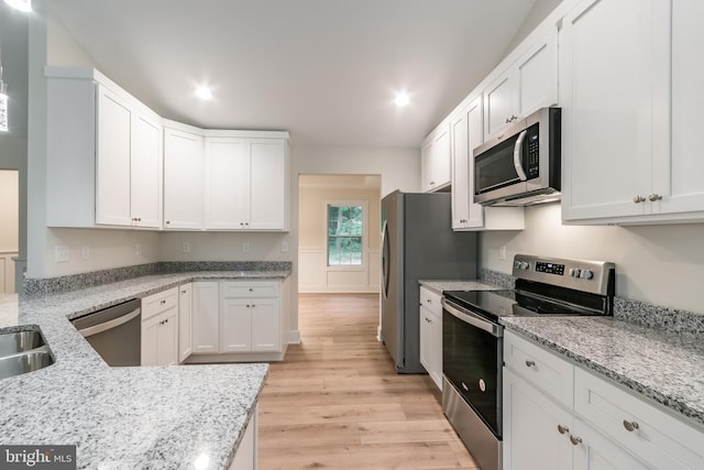 kitchen featuring white cabinets, appliances with stainless steel finishes, light wood-type flooring, and light stone counters