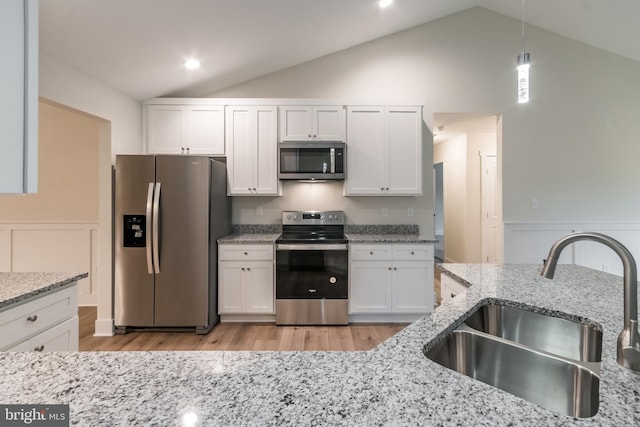 kitchen with white cabinets, sink, light wood-type flooring, decorative light fixtures, and stainless steel appliances