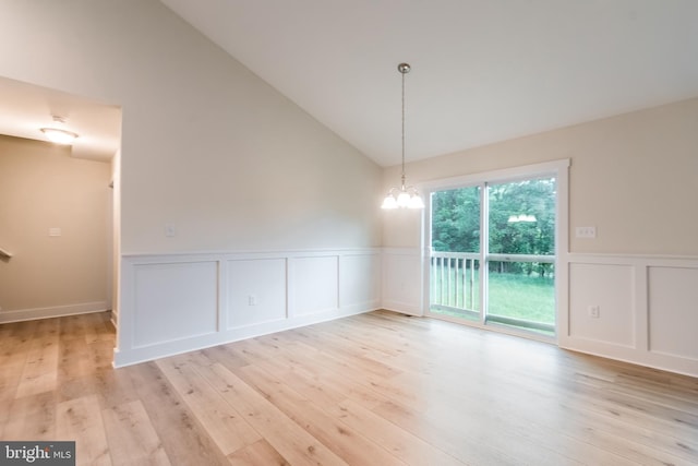 unfurnished dining area featuring a notable chandelier, light hardwood / wood-style floors, and high vaulted ceiling