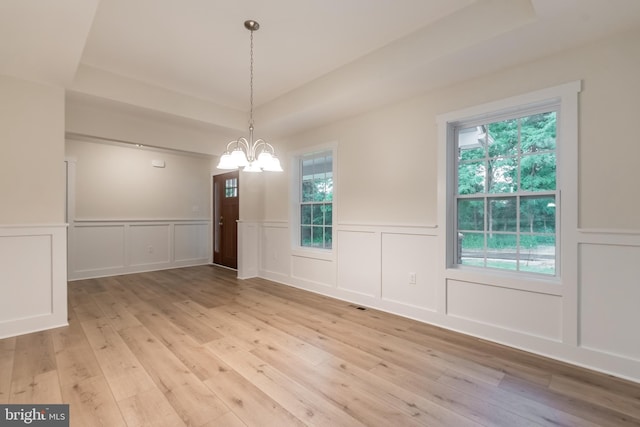 unfurnished dining area with a chandelier and light hardwood / wood-style flooring