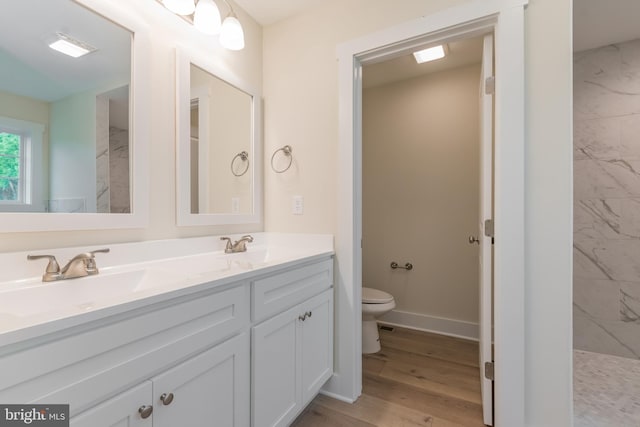 bathroom featuring a tile shower, toilet, vanity, and hardwood / wood-style flooring