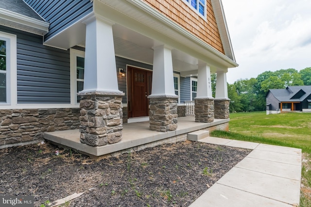 entrance to property featuring a lawn and a porch