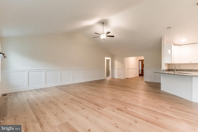 unfurnished living room with ceiling fan, light hardwood / wood-style floors, sink, and vaulted ceiling