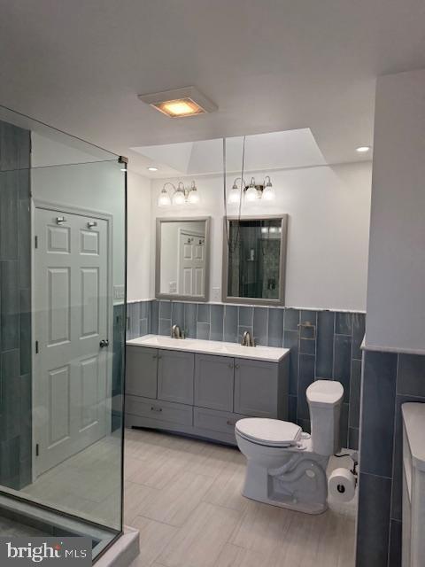 bathroom featuring an enclosed shower, vanity, toilet, and tile walls