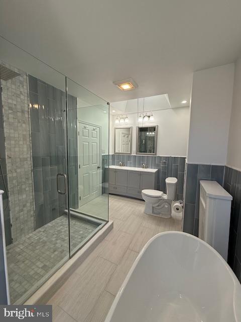 bathroom with vanity, shower with separate bathtub, and tile walls