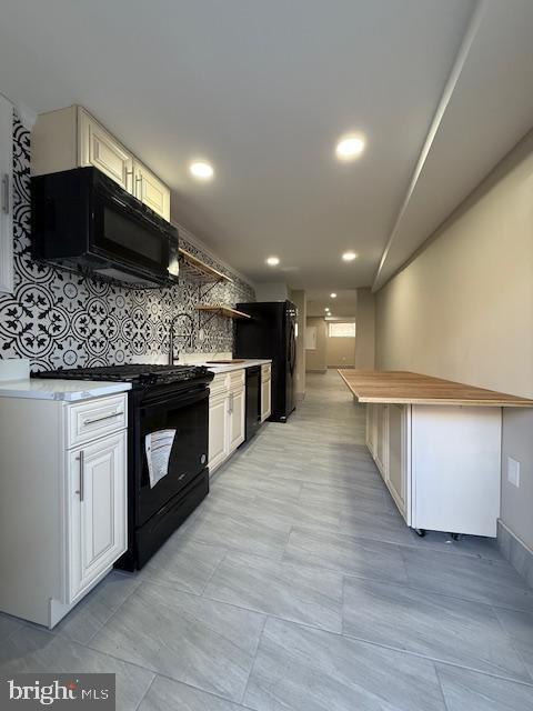 kitchen featuring decorative backsplash, sink, white cabinets, and black appliances