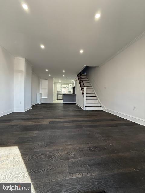 unfurnished living room with dark hardwood / wood-style flooring and ornamental molding