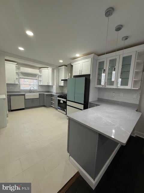 kitchen featuring white cabinetry, sink, kitchen peninsula, decorative light fixtures, and appliances with stainless steel finishes