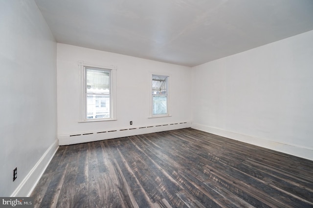 unfurnished room with baseboards, dark wood finished floors, and baseboard heating