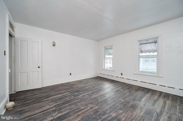 spare room with a baseboard radiator, dark wood-style flooring, and baseboards