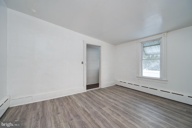 spare room with a baseboard heating unit, a baseboard radiator, wood finished floors, and baseboards