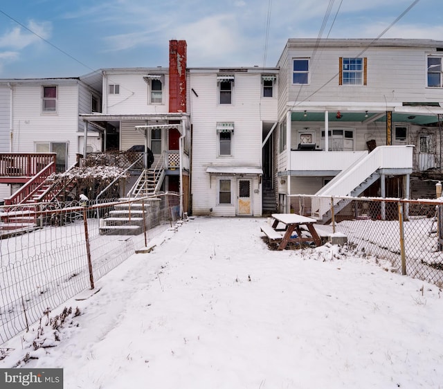 snow covered rear of property with fence