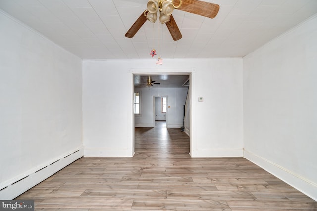 spare room featuring ornamental molding, baseboards, light wood finished floors, and baseboard heating