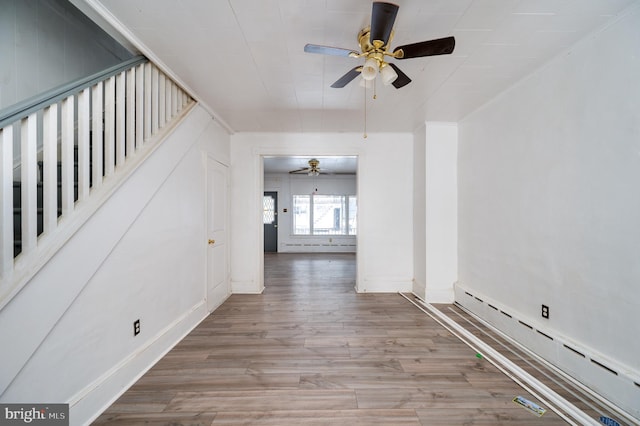 hallway with baseboards, a baseboard heating unit, and wood finished floors