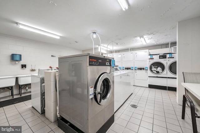 washroom featuring independent washer and dryer, light tile patterned floors, stacked washer and clothes dryer, and sink