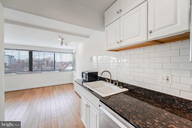 kitchen featuring sink, dark stone counters, decorative backsplash, white cabinets, and light wood-type flooring