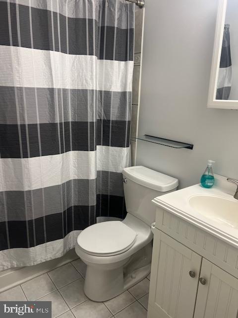 bathroom with toilet, vanity, and tile patterned floors